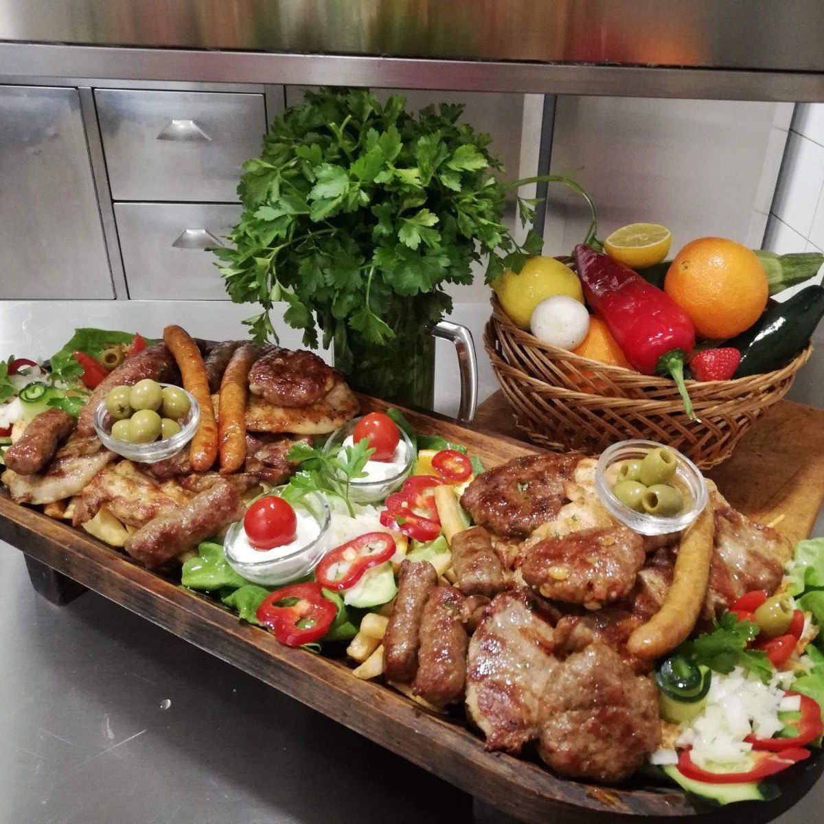 Meso sa roštilja i salata u dugom drvenom koritu, pored korpe sa povrćem i voćem