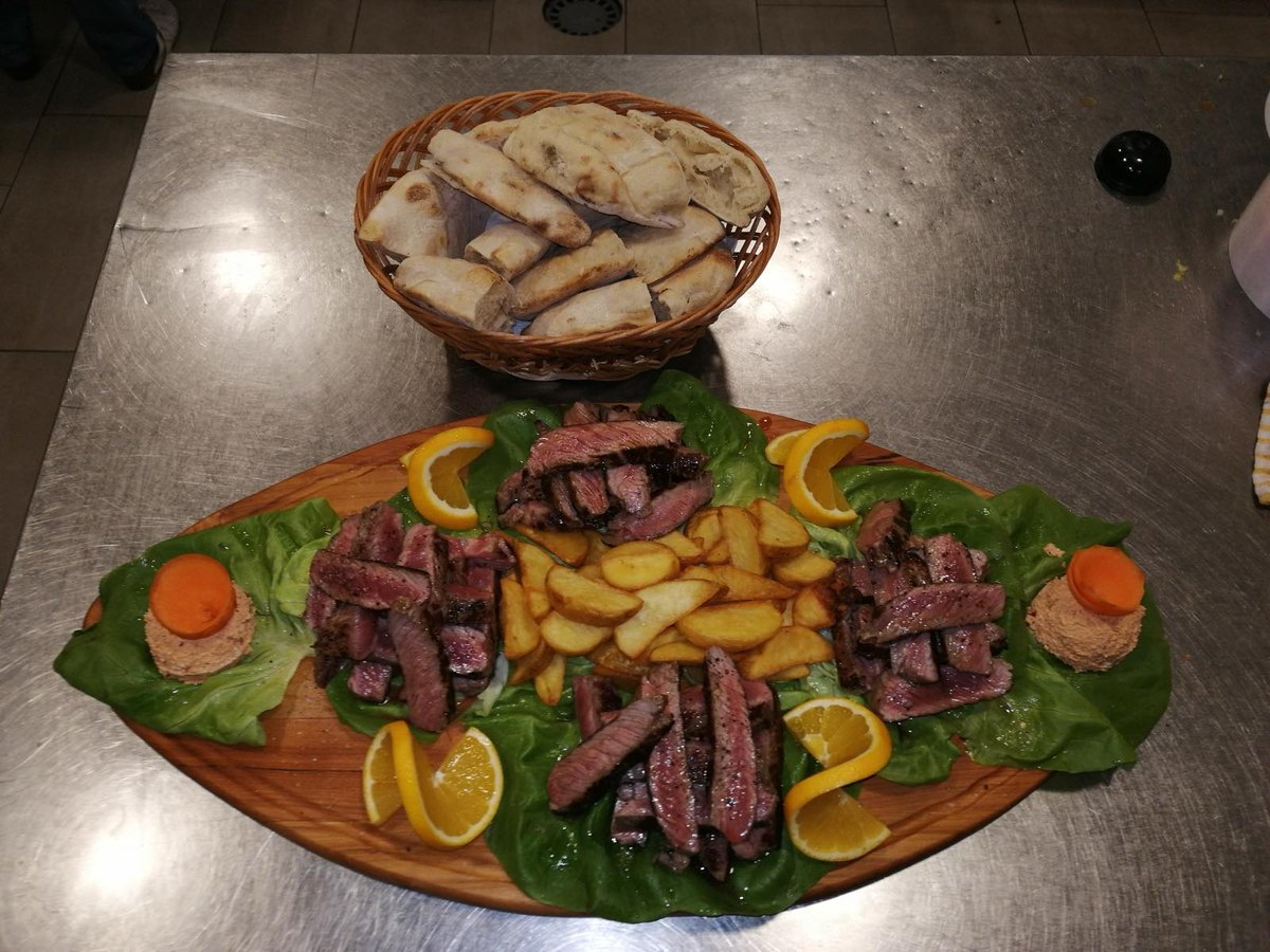 Ramstek narezan na dasci, sa pečenim krompirom, narandžom i korpom lepinja